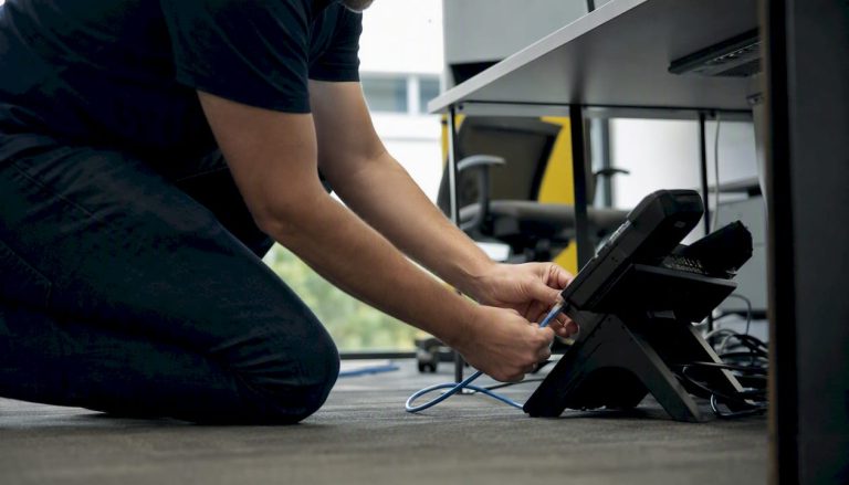 Hands connecting VoIP phone cables for setup