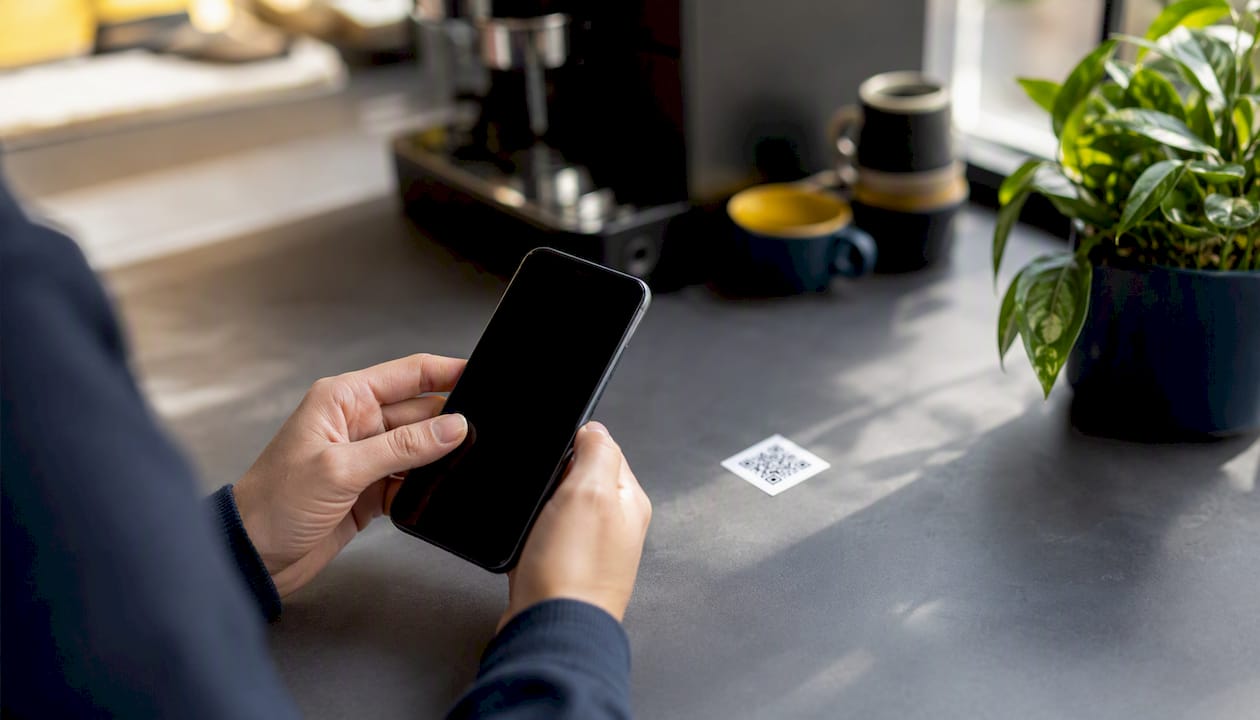 Hands holding smartphone near QR code card
