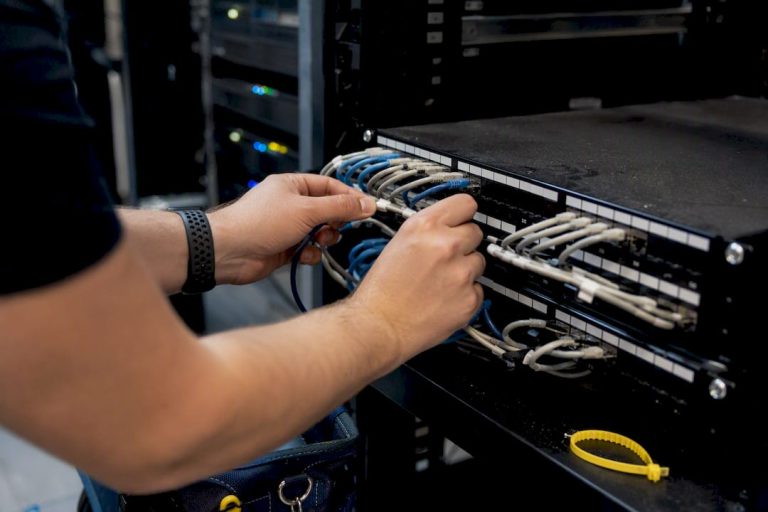 Hands connecting network cables in server rack