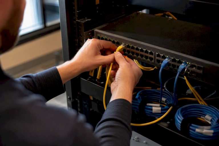Hands connecting Ethernet cable to PoE switch