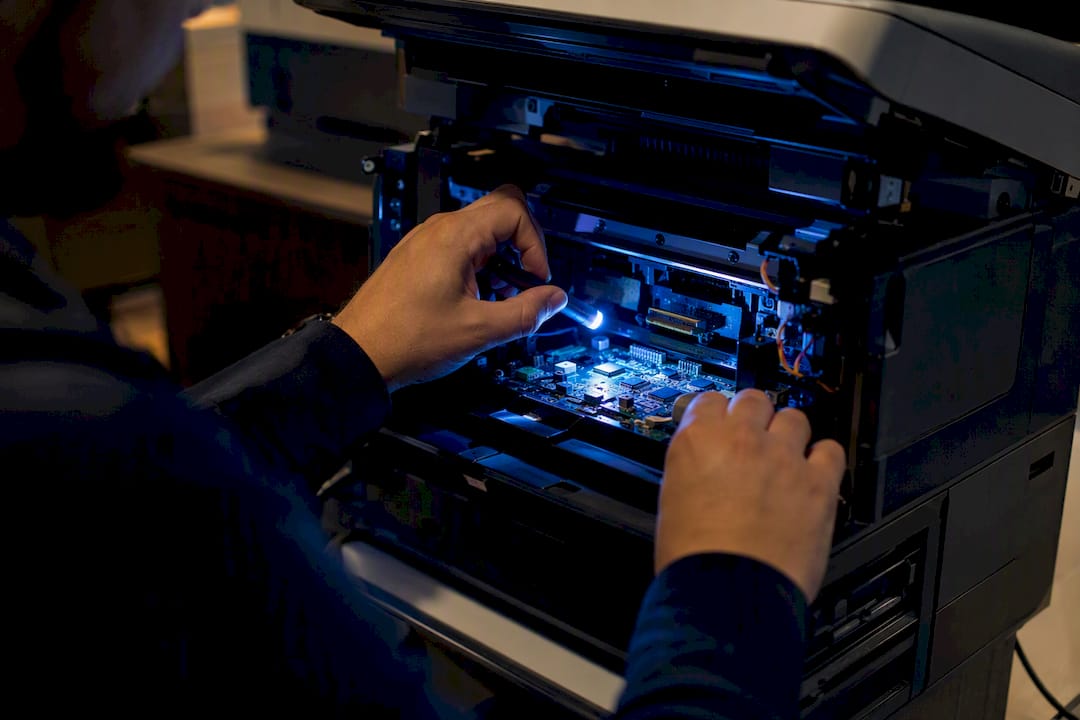 Close-up of hands inspecting printer electronics