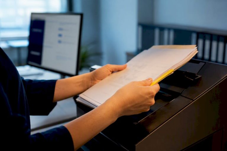 Hands feeding documents into office scanner